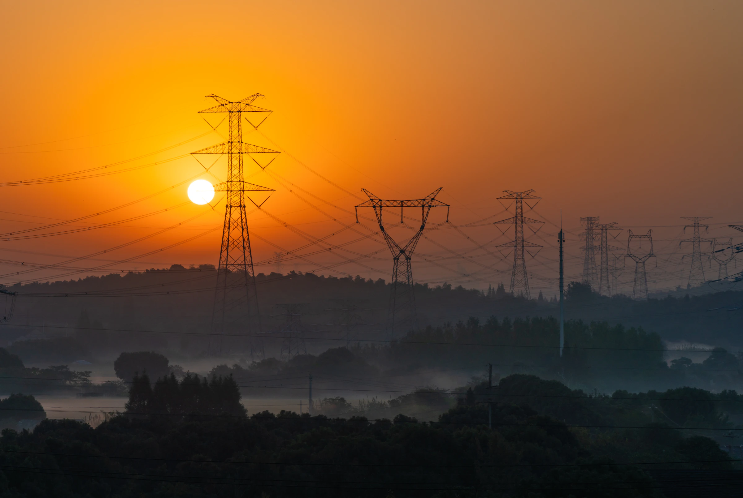 Power pylons marching into a misty sunrise.